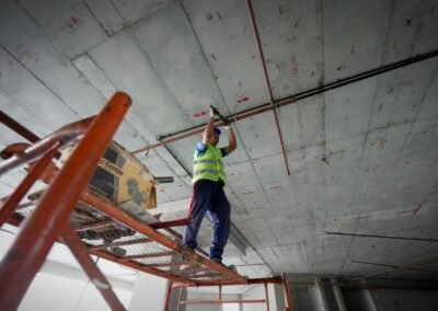 a man standing on a ladder working on a ceiling